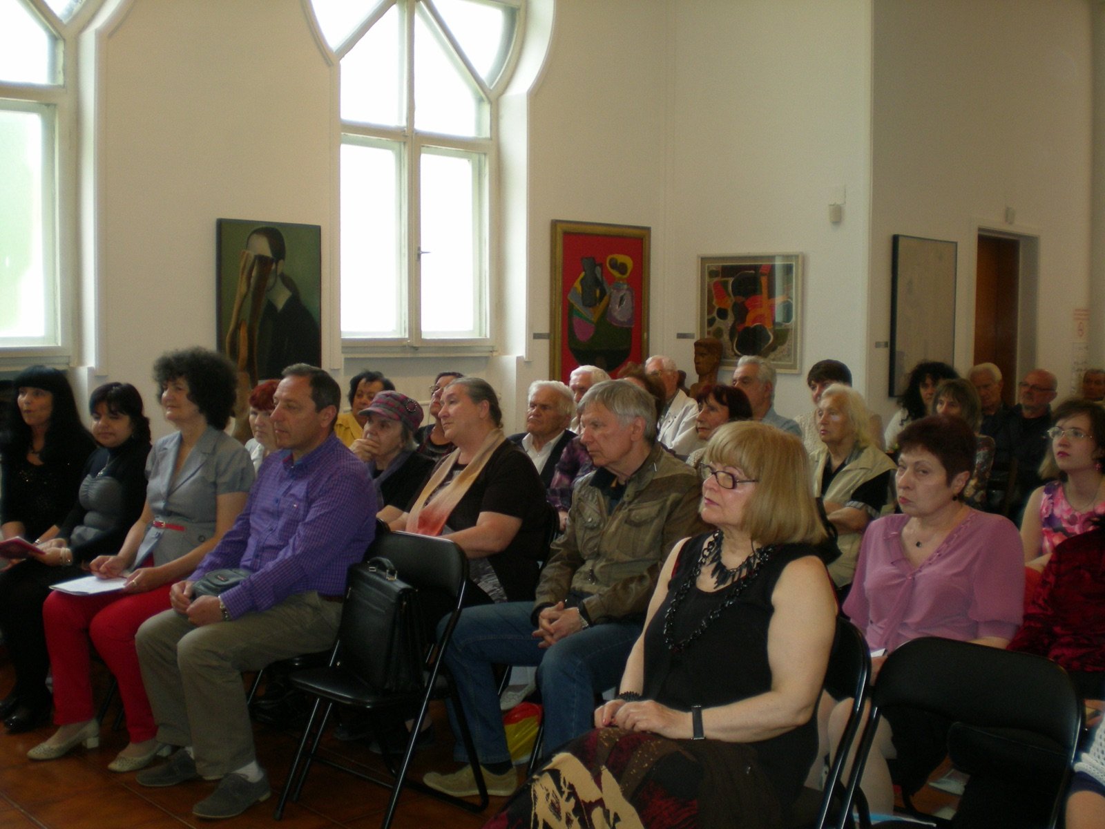 The audience at the launch, in a hall hung with paintings